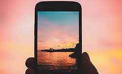 PHand holding phone camera with beautiful sunset
