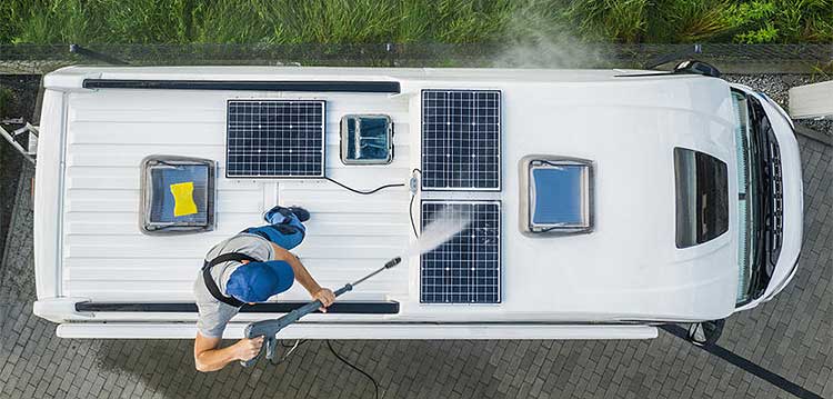 Man cleaning solar panels on roof of motorhome