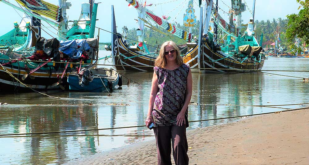 Leslie on beach in Bali with boats in background